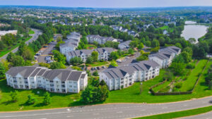 Aerial Exterior of Acclaim at Ashburn, neighborhoods in the background, lush foliage, photo taken on a sunny day.