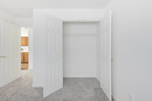 Interior Unit Bedroom Closet, neutral toned carpeting, white walls.