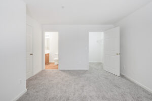 Interior Unit Bedroom, attached bath, neutral toned carpeting, white walls.