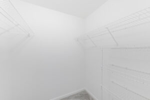 Interior Unit Closet, Neutral toned carpeting, clothes rack, whitet walls.