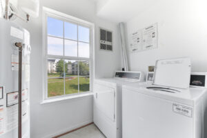Interior Laundry facilities, white walls, white appliances, large window.