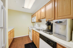 Interior Community Kitchen, light brown cabinets, stainless steel sink, wood floors.